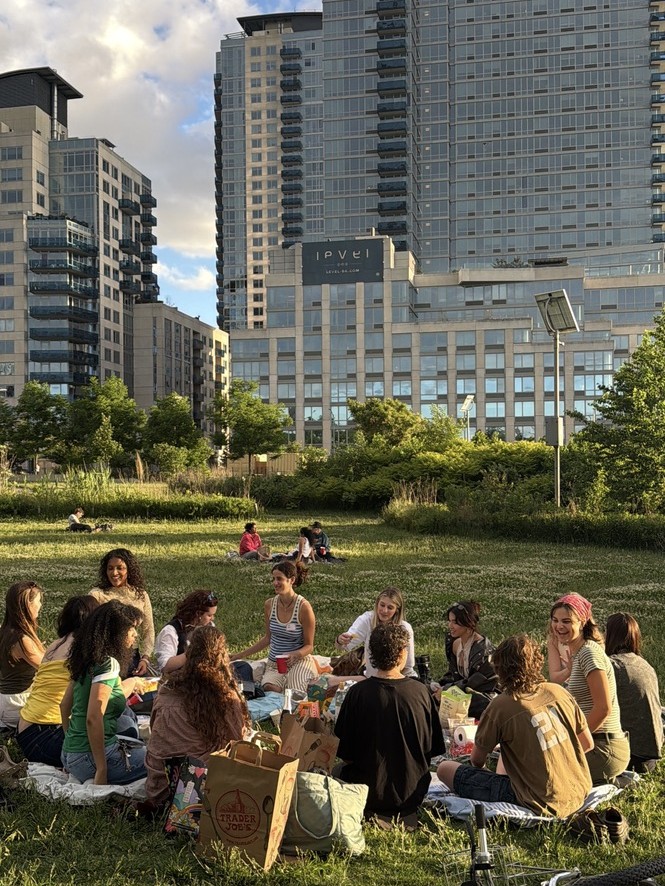 Friends sitting on blankets in a city park with towers behind them
